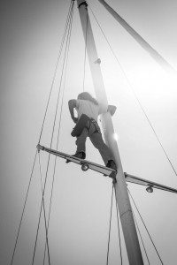 Man up on the mast of a sailboat.