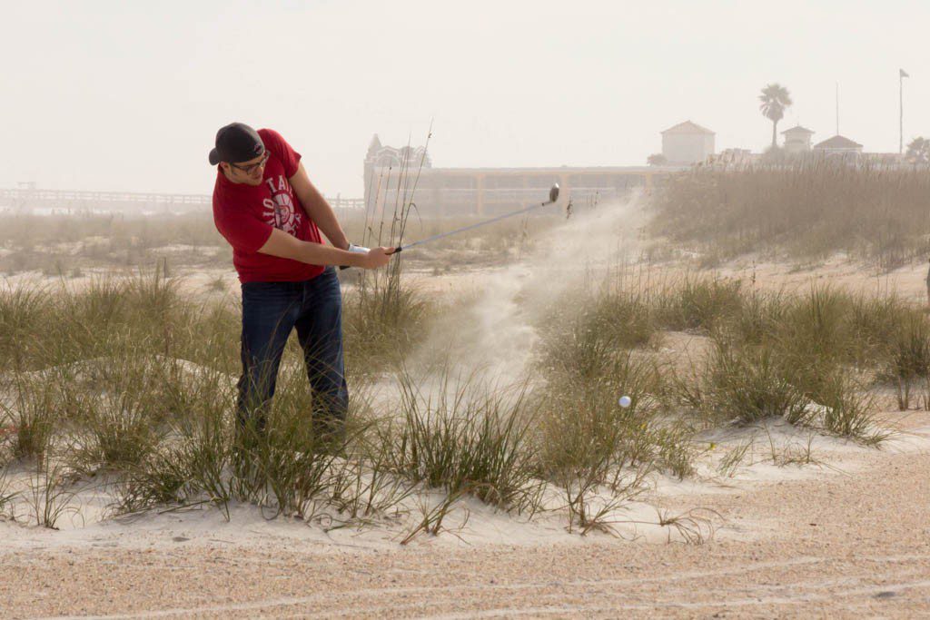 Just a random dude golfing on the beach.