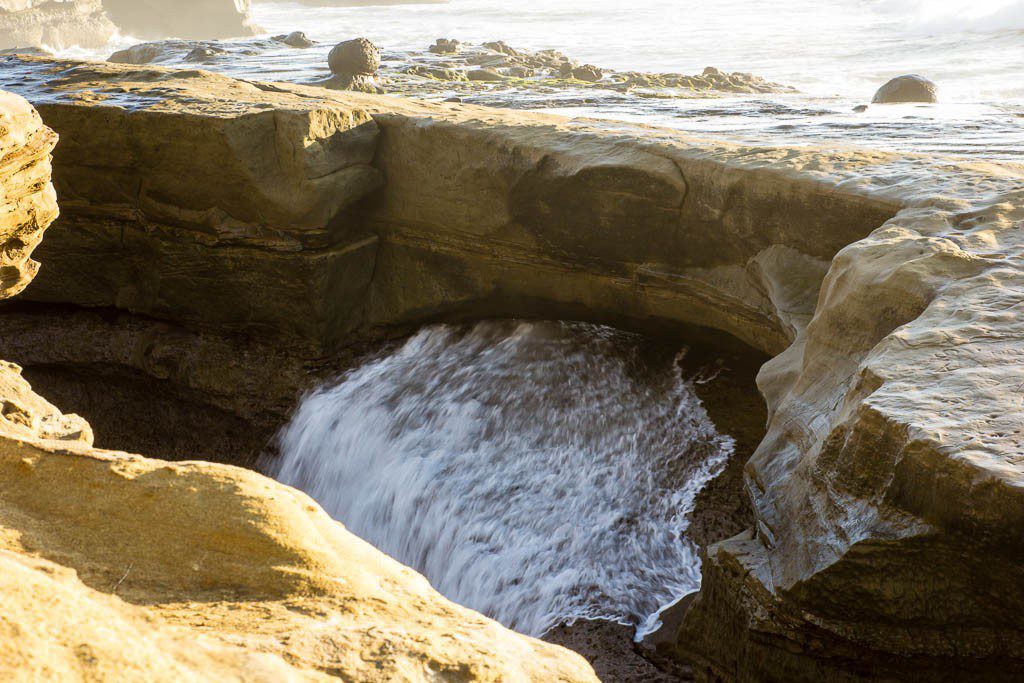 Waves gushing through a hidden rock bridge