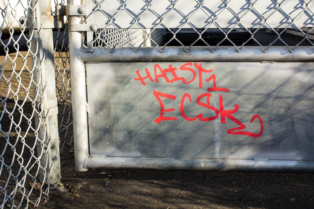 Red writing and chainlink fence